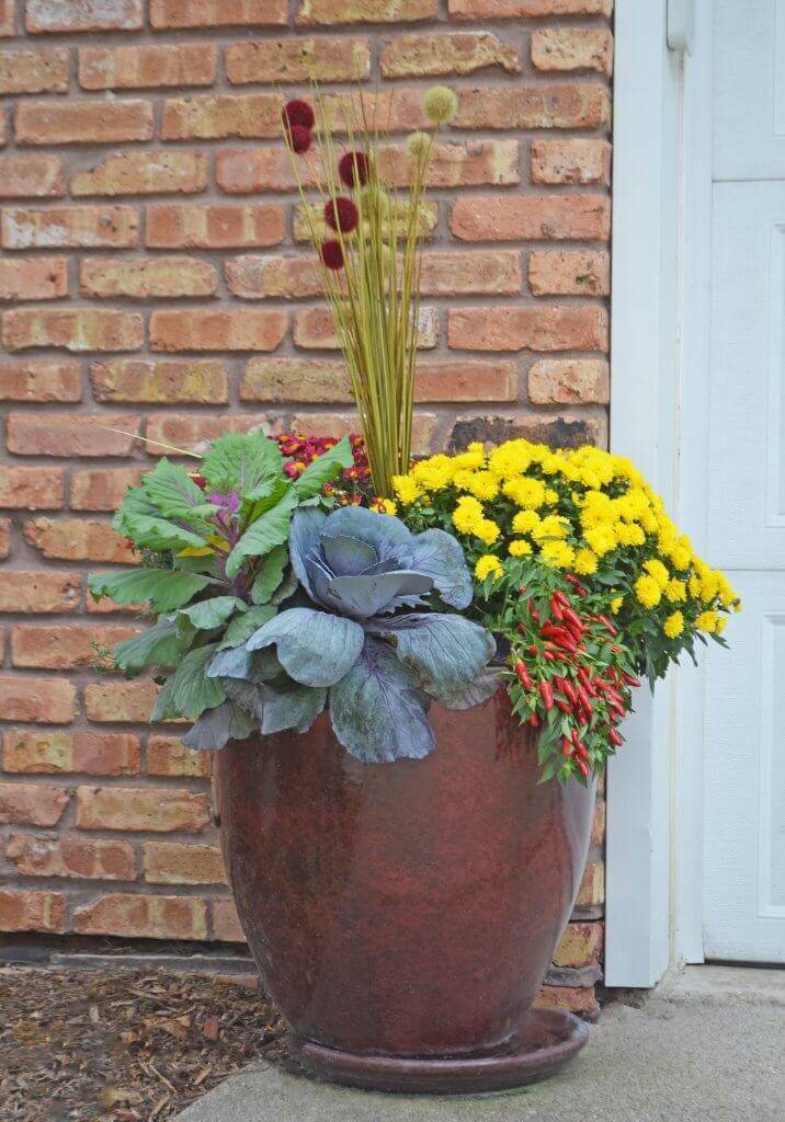 Copper planter filled with yellow and green flowers.