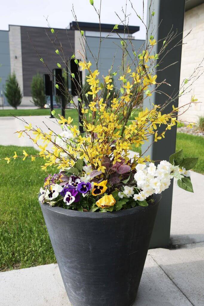 Entryway planter with purple and yellow flowers.
